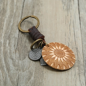 Braided leather keychain with engraved geometric pattern and metal pendants