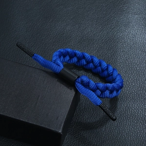 Close-up of royal blue braided bracelet with black aglets and DPANCO logo detail