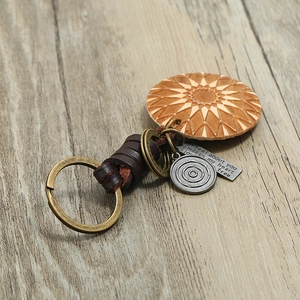 Handmade leather keychain with carved wood geometric sunburst and vintage bronze pendants
