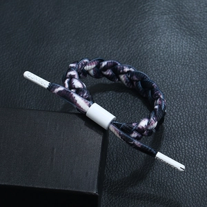Macro view of purple and white braided cord bracelet with adjustable slide buckle and logo
