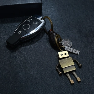 Retro handmade leather robot keychain with engraved metal tag on a black textured surface