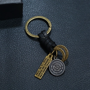 Vintage punk woven leather keychain with antique bronze charms on black textured surface