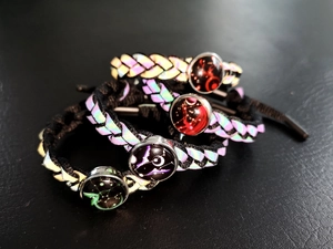Dettaglio di quattro bracciali intrecciati riflettenti con ciondoli olografici in vetro
