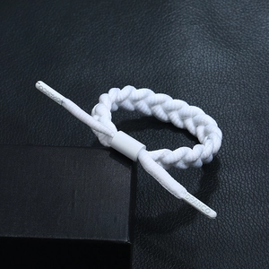 Close-up of a white braided rope bracelet with engraved DPANCO logo aglets on black leather