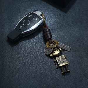 Detail of a vintage punk robot keychain with woven leather strap and metal quote tag