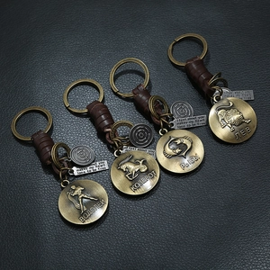 Detail of vintage woven leather zodiac keychains with bronze charms on leather background