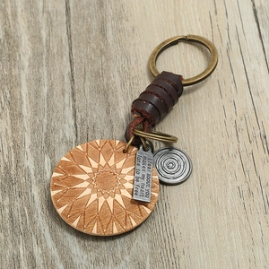 Retro leather braided keychain with geometric sun wood carving and metal tag on wood