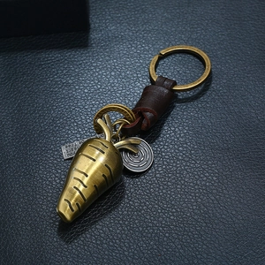 Vintage bronze carrot keychain with leather wrap and engraved metal charms on black base