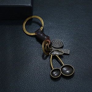 Retro cherry pendant keychain with woven leather strap and bronze metal accents