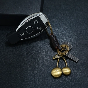 Vintage brass cherry keychain with woven leather accents and engraved metal tag