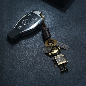 Punk woven leather keychain with movable bronze robot pendant and car key on leather background