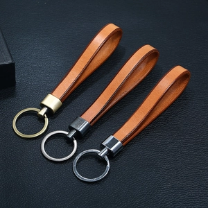 Three vintage leather keychains with bronze and silver hardware on a black surface