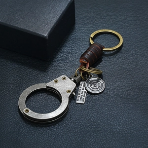 Vintage handcuff keychain made of bronze alloy and brown leather on black texture