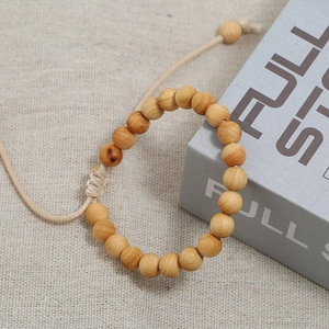 Natürliches Holzperlenarmband mit verstellbarer Kordel auf Leinenhintergrund