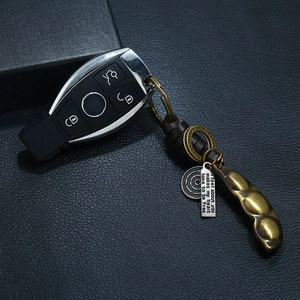 Vintage bronze pea pod pendant keychain with dark brown leather strap on leather background
