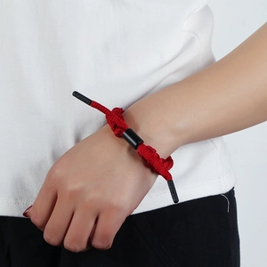 Minimalist red braided rope bracelet with black cylinder bead and branded aglets on wrist