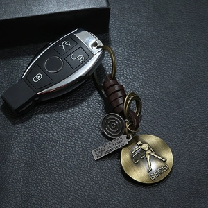 Detail of vintage braided leather keychain with bronze Libra zodiac tag and engraved charms