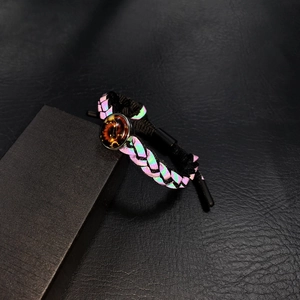Dettaglio macro del bracciale olografico intrecciato con ciondolo zodiacale luminoso
