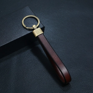 Vintage brown leather keychain with antique bronze metal ring on dark leather background