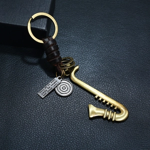 Retro saxophone keychain with woven brown leather and engraved charms on black background