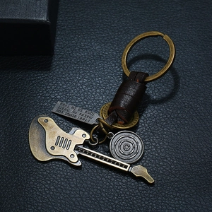 Retro braided leather guitar keychain with bronze alloy charms on black texture