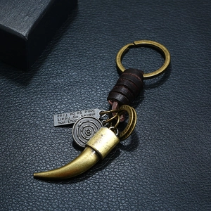 Punk vintage braided leather keychain with antique bronze charms on black surface