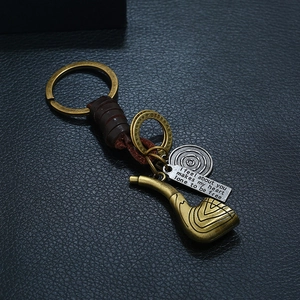 Retro punk braided leather keychain with vintage bronze pipe pendant on black background