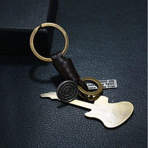 Vintage woven leather keychain with bronze guitar pendant and engraved tag on black texture