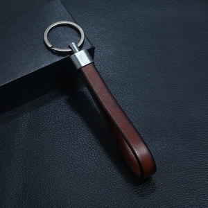 Close-up of retro reddish-brown leather keychain with vintage silver ring and gift box
