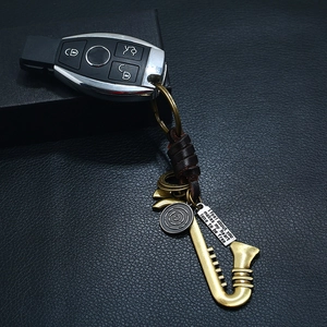 Retro saxophone leather keychain with engraved bronze charm and woven strap on black background