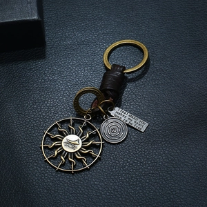 Vintage leather keychain with bronze sun pendant and engraved metal charms on black leather