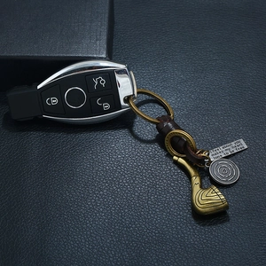 Vintage braided leather keychain with bronze pipe charm and engraved metal tag on black leather