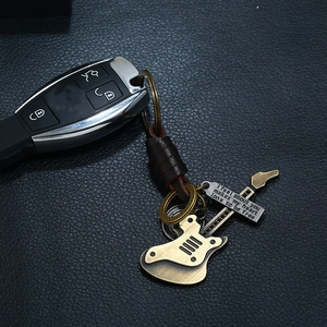 Retro guitar alloy keychain with braided leather strap on black leather background