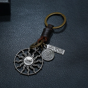 Macro shot of vintage braided leather keychain with sun pendant and engraved metal tag