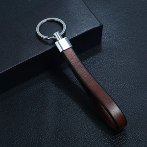 Macro detail of dark brown leather texture and polished silver metal key ring finish