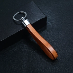 Close-up of caramel brown genuine leather keychain with polished silver metal ring on black box