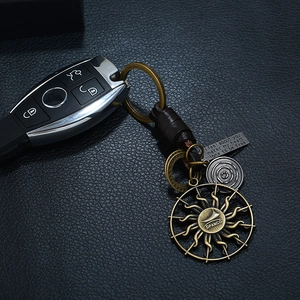 Vintage leather keychain with sun pendant and engraved plaque on a car key