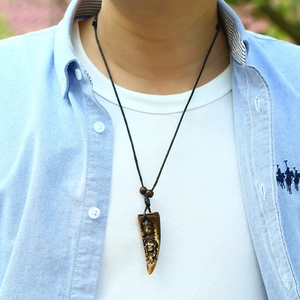 Close-up of a tribal resin pendant necklace with hand-carved face and black cord