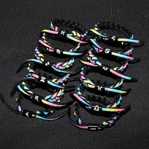 Detail of 12 zodiac woven bracelets with rainbow gradient colors on a black background
