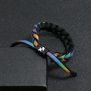 Macro detail of rainbow woven bracelet with Sagittarius zodiac symbol on black sliding buckle