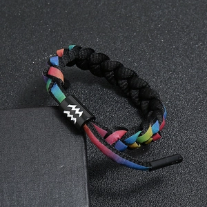 Close-up of braided Aquarius zodiac bracelet with colorful rainbow webbing on black background
