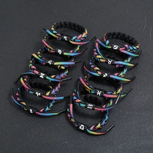Braided rainbow zodiac bracelets with white constellation symbols on black cylinders
