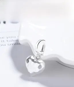 Macro view of S925 sterling silver heart pendant with irregular hammered texture on white tray