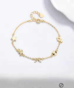 Détail d'un bracelet en argent S925 doré avec breloques étoile, lapin, nœud, pomme et note