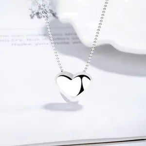 Close-up of polished 925 silver heart pendant necklace on a minimalist book background