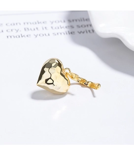 Macro shot of 925 silver gold-plated heart earring with textured hammered finish