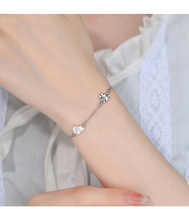 Close-up of silver chain bracelet with hammered texture heart pendants on wrist