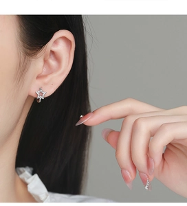 Close-up of model wearing star-shaped sterling silver earrings with zircon stones