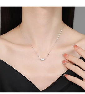 Close-up of 925 sterling silver brushed pea pendant necklace on a woman's neck