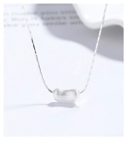 Macro detail of silver pea pendant with sandblasted matte finish on snake chain